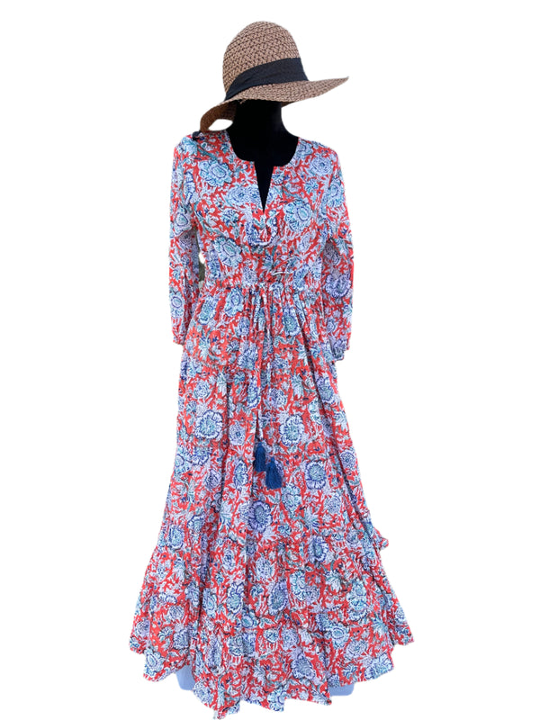 The dress in the image has a vibrant orange base color with blue, white, and purple floral patterns. The combination of these colors gives it a bold, lively, and eye-catching look, perfect for a bohemian or vintage-inspired style.