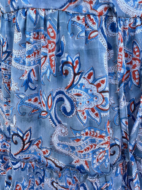 the image has a soft blue base color with orange, white, and navy blue paisley patterns